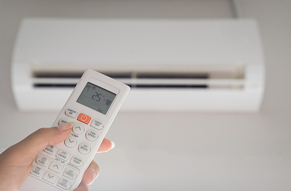 Ar condicionado com uma mão a usar o comando para ajustar a temperatura para 25°C